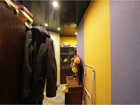 куртка на дверце шкафа для одежды, сушилка для белья и трельяж в прихожей квартиры жилого дома с выходом на крышу магазина