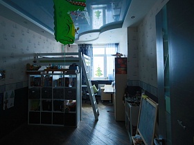 натяжной голубой потолок в детской комнате с белым мебельным гарнитуром у светлых стен квартиры студии молодой семьи в современном мегаполисе