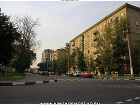 припаркованные машины на проезжей части дороги первого Кожуховского переулка у двухцветного бардюра вдоль пешеходного тротуара и жилых многоэтажных домов