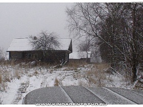 машина на улице с поворотом вдоль старых заброшенных деревянных домов с белыми крышами от снега в Калашниково