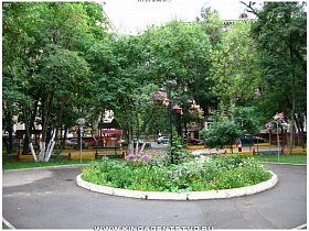 круглая цветочная клумба в уютном  дворе кирпичных пятиэтажек