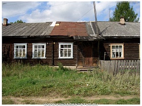 белые рамы окон старого деревянного дома с крыльцом и крышей,частично покрытой железными листами вдоль натоптанной дорожки в Переславле