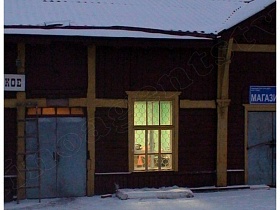 железные входные двери в здание вокзала с коричневыми стенами одноэтажного дома под заснеженной крышей с белой вывеской
