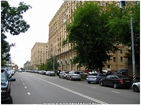припаркованные машины на городской дороге у высотного многоквартирного сталинского дома