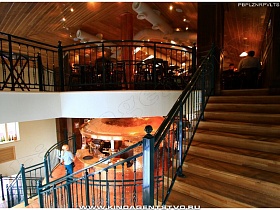 переход из одного зала на первом этаже на просторный на втором по деревянной лестнице с металлическими перилами паба с медной бочкой