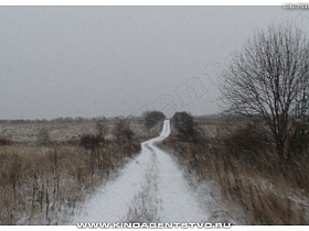 длинная извилистая проселочная дорога, засыпанная белым снегом на заросшем пустыре