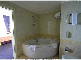 угловая ванна с душем в ванной комнате с красивой плиткой на стенах и на полу высотного отеля