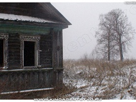 деревянные наличники на окнах без стекол старого забошенного деревянного дома на заснеженном участке с высокими деревьями в Калашниково