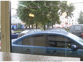 многочисленные припаркованные машины вдоль зеленой аллеи из окна чебуречной, забегаловке, рюмочной