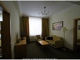 торшер и журнальный столик у дивана с креслом в гостиной номера отеля