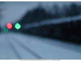 огни светофора на широкой улице под снегом на железнодорожной станции через обледеневшее стекло машины