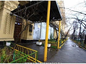 желто зеленый забор полисадника у входной двери с навесом сталинки