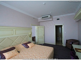 большая светлая кровать с разноцветными подушками в спальне красивого номера высотного отеля