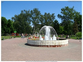 круглый фонтан на небольшой городской площади в окружении зеленых деревьев в Ивантеевке
