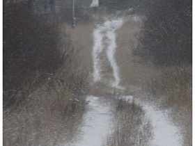 проселочная дорога под снегом, ведущая в небольшую заброшенную деревню на холме в Калашниково