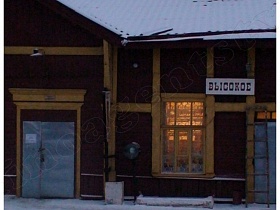 свет за окном железнодорожного вокзала в коричневом одноэтажном здании с белой вывеской на деревянных балках