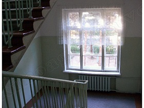 окно с короткой гардиной на чистой лестничной площадке школы в Алексино