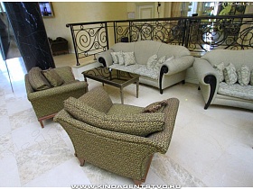 мягкие диваны с подушками и кресла с журнальным столиком возле кованых перил в отеле высотного здания