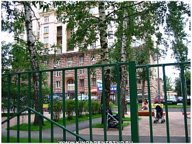 зеленый металлический забор вокруг детской площадки во дворе сталинского здания
