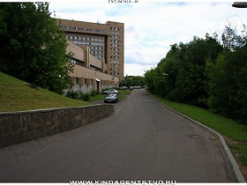 автомобильная дорога вдоль многоэтажного корпуса большой больницы в зеленом массиве