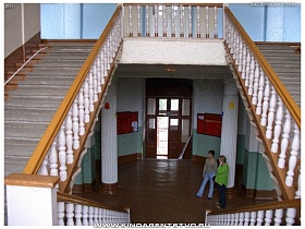двусторонняя лестница с белыми рельефными перилами в коридоре у входной двери в помещение общеобразовательной школы №1