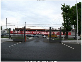 открытые железные ворота в высоком заборе на территорию частной клиники