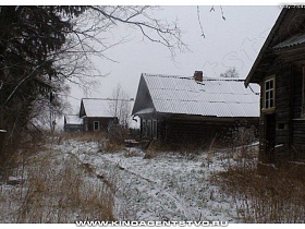 деревянные старые дома на участках без забора вдоль небольшой улицы в Калашниково в зимнее время