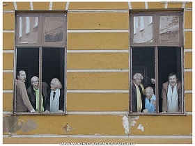 удивленные лица людей за окном городского здания