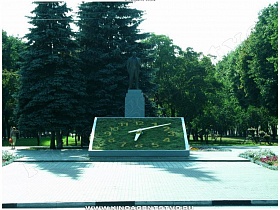 Зеленые цветочные часы с цифрами и длинными стрелками у памятника Ленину в красивом парке Балашиха