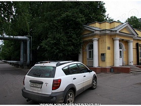 припаркованная машина у крыльца вспомогательного желтого домика интересной постройки на воротах института вдоль Ленинского