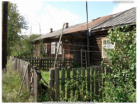 зеленая трава на загороженном участке старого деревянного дома в Переславле