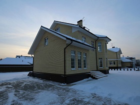 двухэтажное кирпичное здание  с высокими окнами, коричневым цоколем и коричневой крышей на зимнем участке