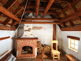 деревянные стулья и скамейка у маленького окна дома мазанки под высокой крышей с деревянными балками
