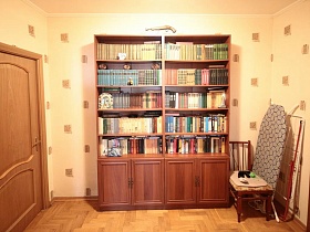 большой шкаф с книгами у стены песочного цвета в просторном холле современной трешки