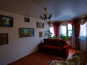 множество картин с природой на леопардовых стенах гостиной с красивыми гардинами на окне в обычной трехкомнатной квартире