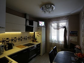 белая мебельная стенка с бежевой столешницей и рабочей поверхностью с отделочной плиткой на кухне современной дизайнерской трехкомнатной квартиры