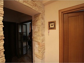 дверной проем в прихожей с элементами декоративного камня на стенах в современой трехкомнатной квартире сталинки