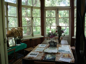 страницы истории,литература, фотографии на столе,старинные деревянные стулья у белых деревянных окон художественной дачи-музей советского времени