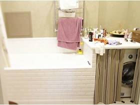стиральная машинка за полосатой шторкой в ванной комнате однокомнатной квартиры в жилом доме