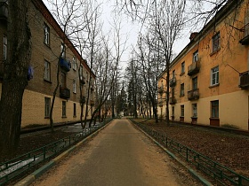 ровная дорога между немецкими трехэтажками с полисадниками за зеленым заборчиком