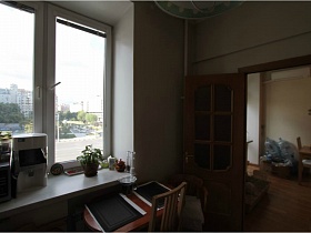 раздвижной стол с салфетками у окна с заставленным подоконником в светлой кухне простой квартиры на Садовом