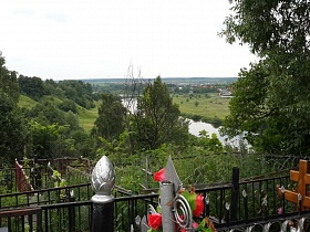 металлические ограды с памятниками и крестами на территории Домодедовского кладбища в зеленой лесной зоне на побережье реки