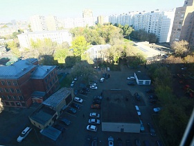 вид из окна квартиры оператора на придомовую территорию с жилыми домами, припаркованными машинами и многоэтажные дома