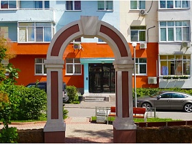 красивая арка на воротах с невысоким забором в алее двора разноцветных пятиэтажек