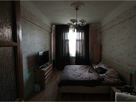 общий вид светлой спальной комнаты с бежевым мебельным гарнитуром через открытую входную дверь для съемок кино