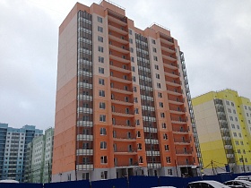 строящиеся разноцветные современные многоэтажные дома за синим забором в новостройке