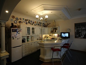 множество декоративных тарелок над шкафами белой кухни