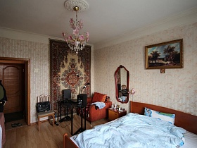 картина над большой кроватью с голубым одеялом, зеркало в рамке над прикроватной тумбочкой в спальной комнате квартиры сталинки