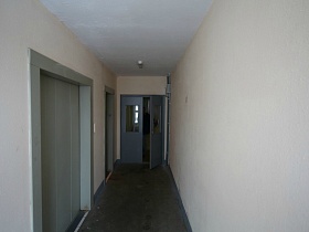 светлые стены коридора с лифтом в современном высотном здании