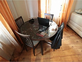 коричневые стулья со спинкой вокруг круглого стола в углу гостиной семейной трешки в Сталинке